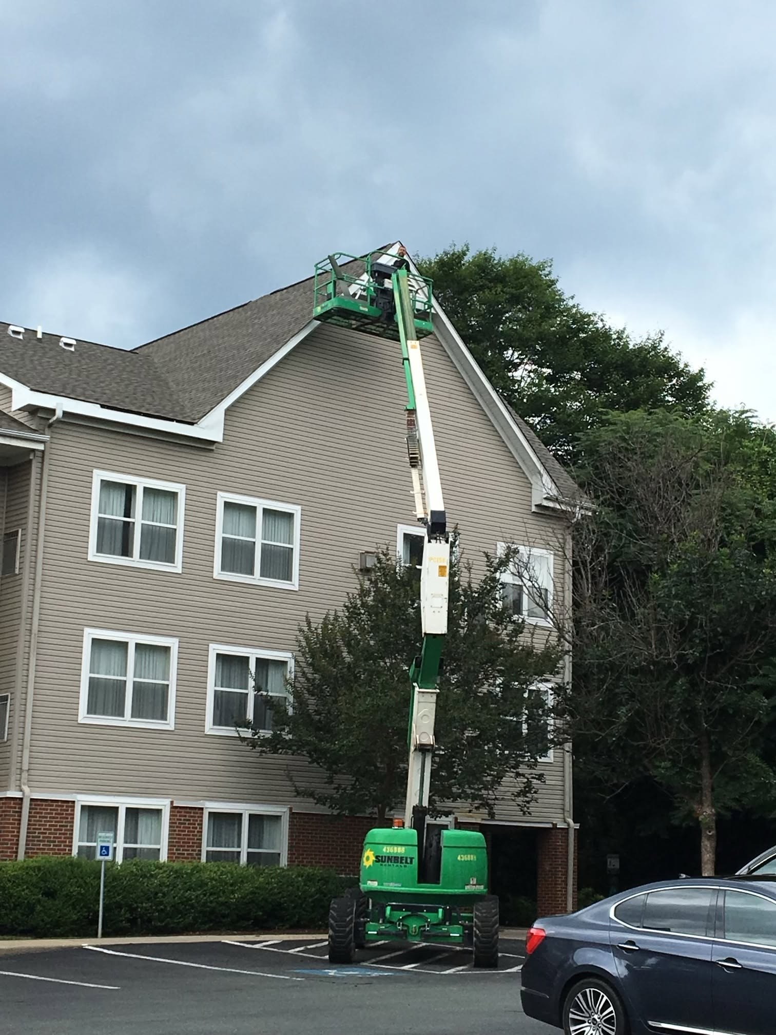 A worker on a lift beside the roof edge of a house.