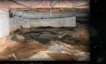 Wet, sagging brown attic insulation hanging off cracked masonry where water leaked in from failing gutters