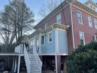 Older red-brick home with light-blue side addition and new white gutters