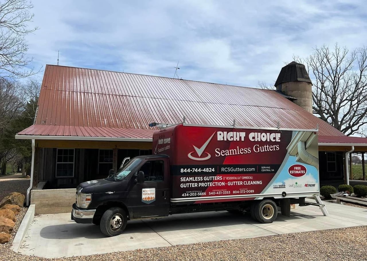 The RCS Gutters branded box truck parked in front of a Central Virginia red-roof barn, full RCS wrap visible